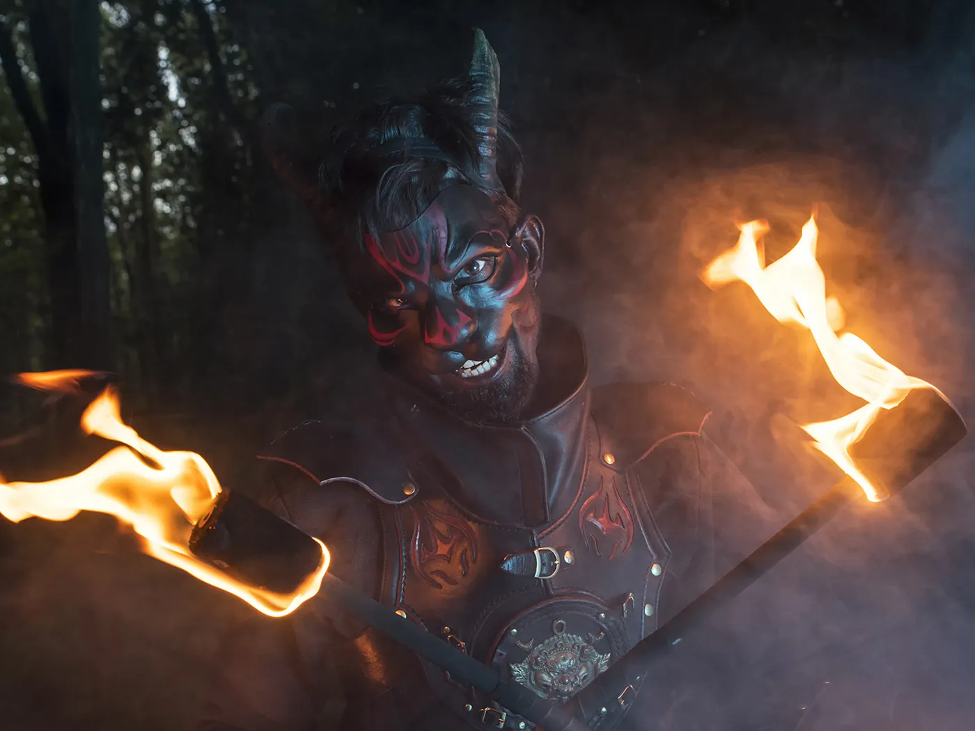 Jongleur de feu en costume de chat, torches enflammées en pleine nuit